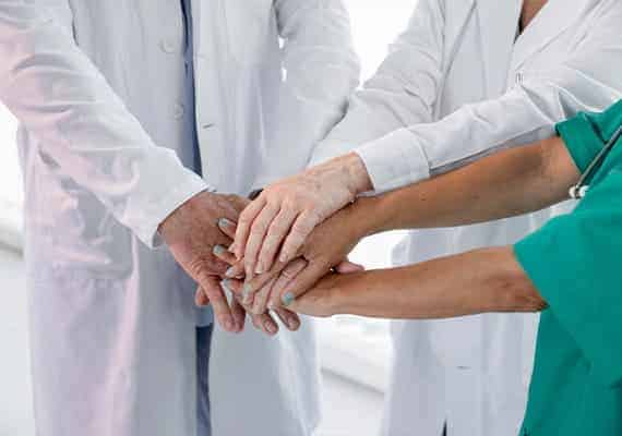 imagem mostra equipe de enfermagem com as mãos unidas, simulando que vão atuar juntos para a cicatrização de feridas em pacientes
